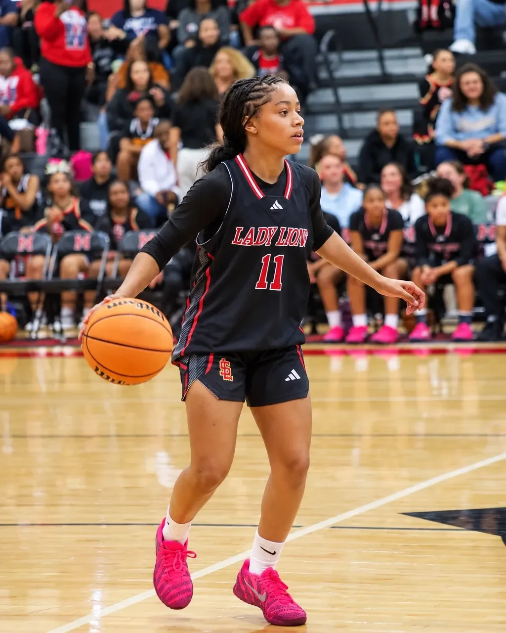 Jordynn Riggins advancing the ball during a competitive basketball game in front of a crowd